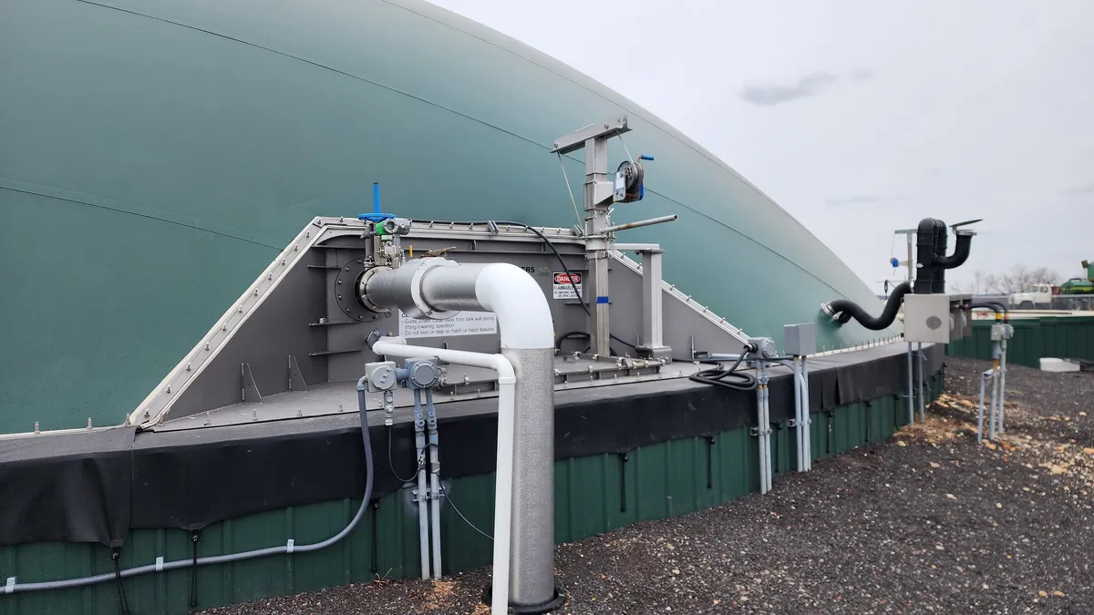 A large anaerobic digestion dome connected to pipes in the ground