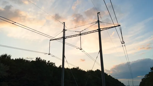 High voltage tower with electric power lines at sunset.