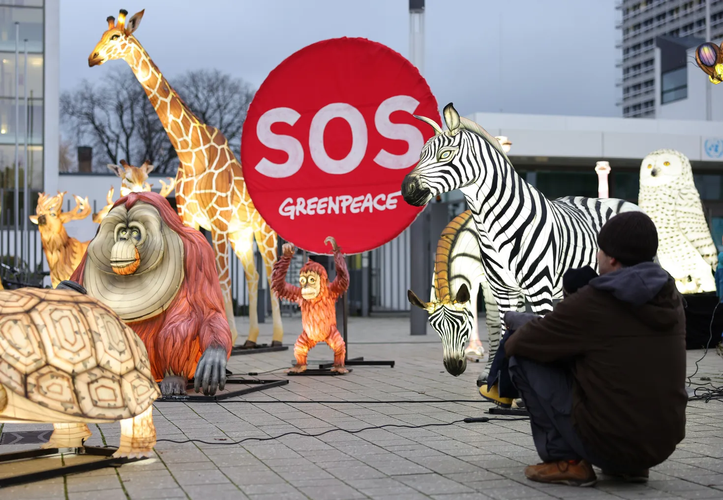 People walk past illuminated effigies of animals