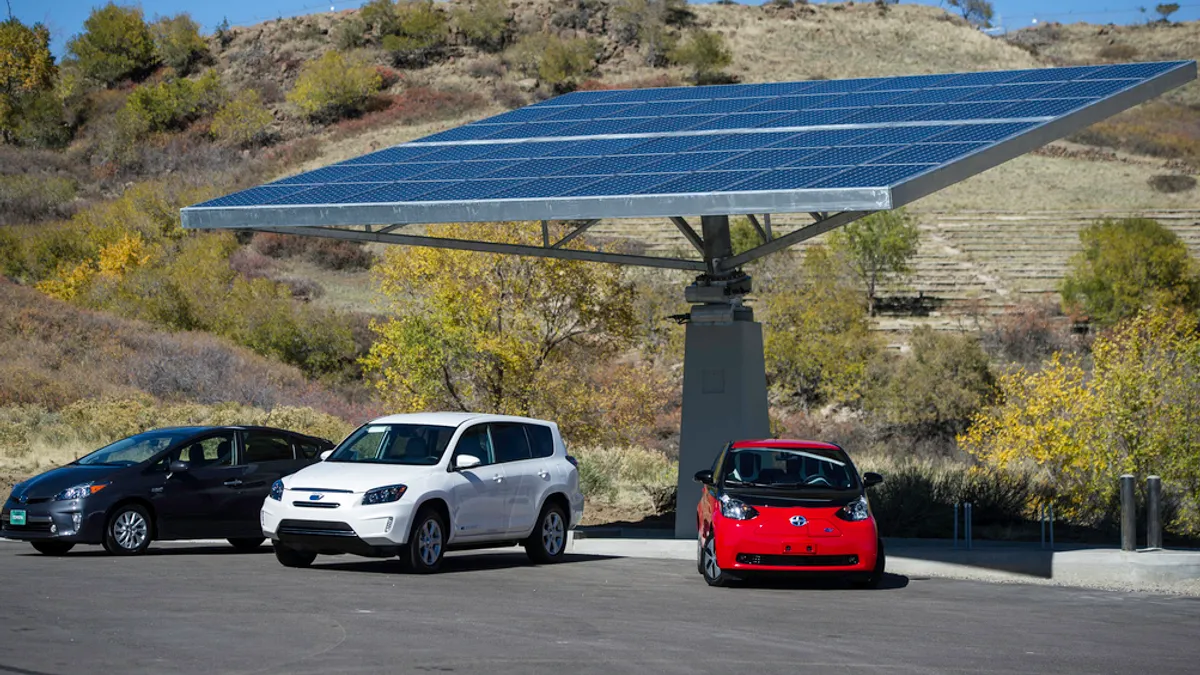 Image shows 3 cars under a solar canopy electric charger.