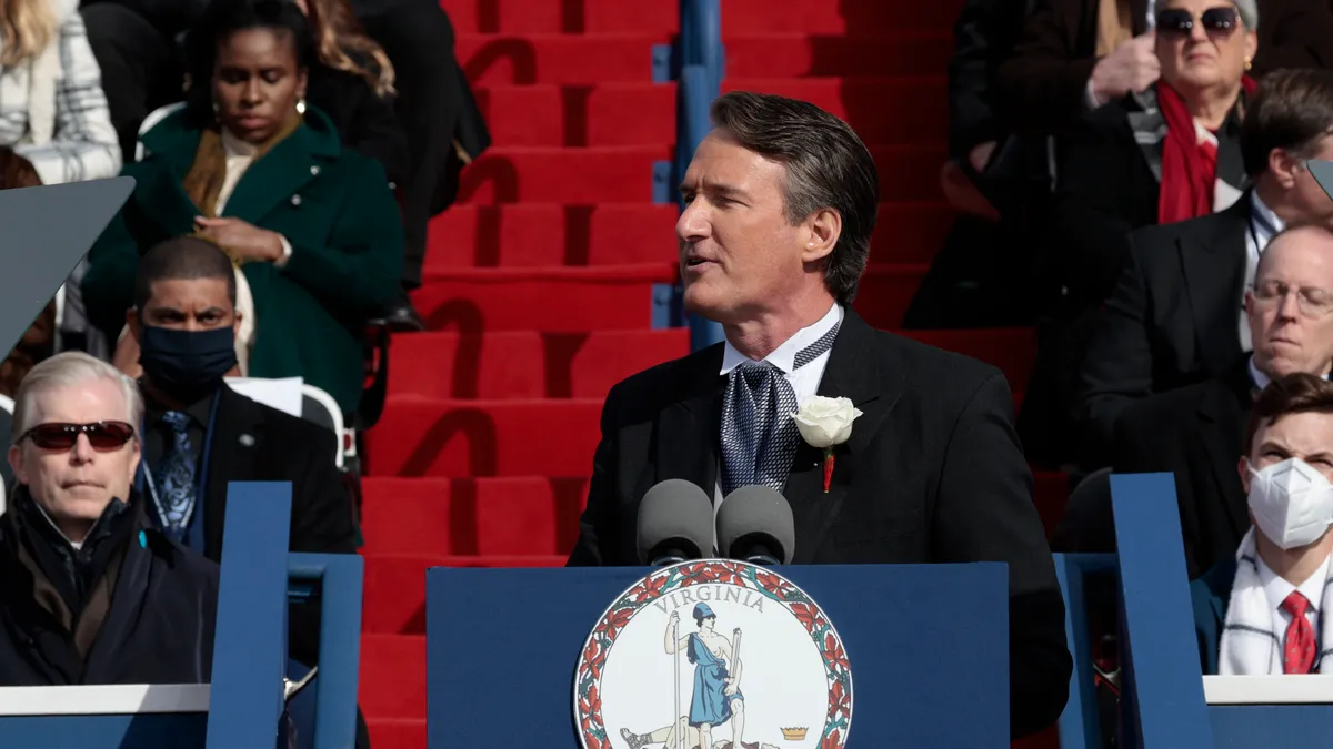 A man at a podium in formal clothes delivers a speech.