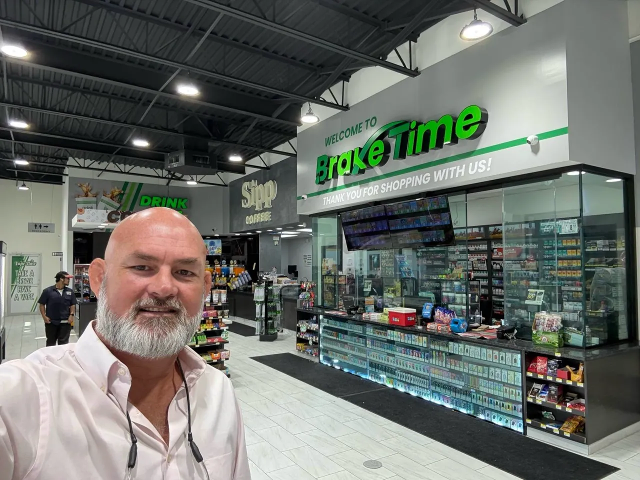 A photo of a person standing inside a convenience store. A sign on the wall says "Welcome to BrakeTime. Thank you for shopping with us!"