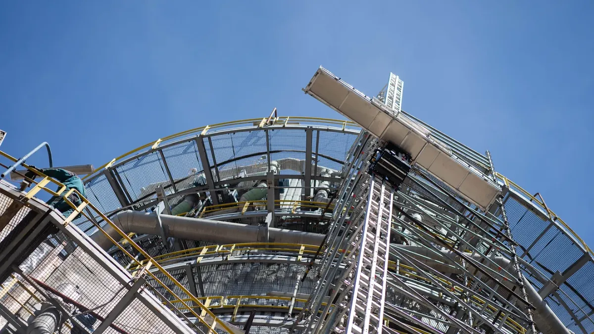 A hoisting robot climbs scaffolding at an industrial site.