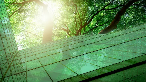 Sustainable glass office building with trees for reducing carbon dioxide.