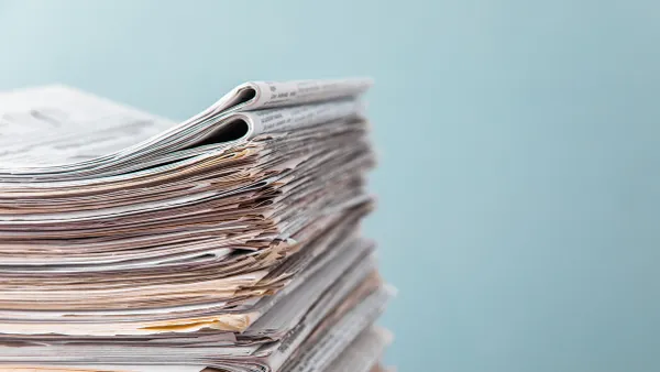 A stack of newspapers are seen against a blue background.