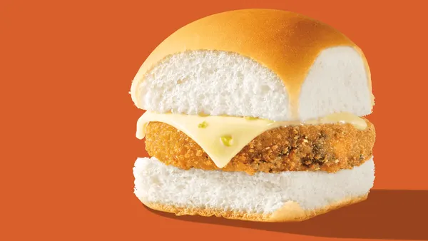 A close up image of a veggie slider with white bun and jalapeno cheese. There is a orange background