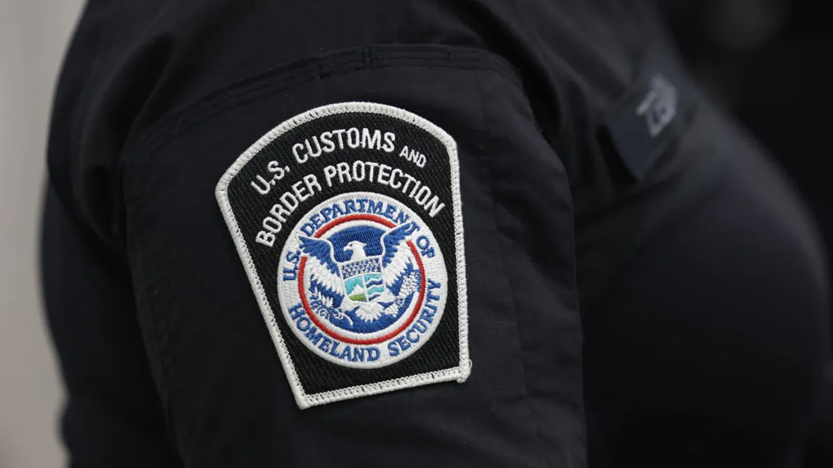 A U.S. Customs and Border Protection badge is displayed on a sleeve.