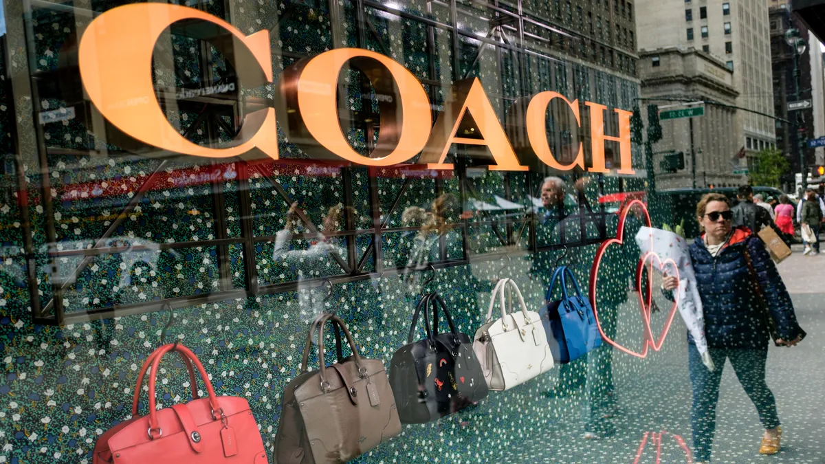 A person walks past Coach bags in a window of Macy's store.