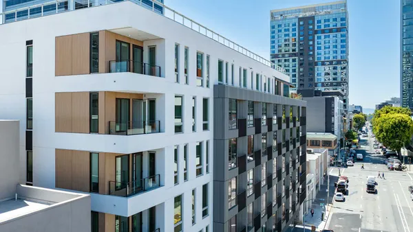 Exterior picture of upper floor of a modern, white apartment building with corner balconies