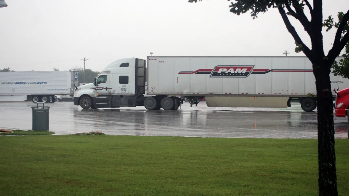 A P.A.M. Transport tractor-trailer sits parked at a rest area in Texas by other trucks amid a heavy downpour.