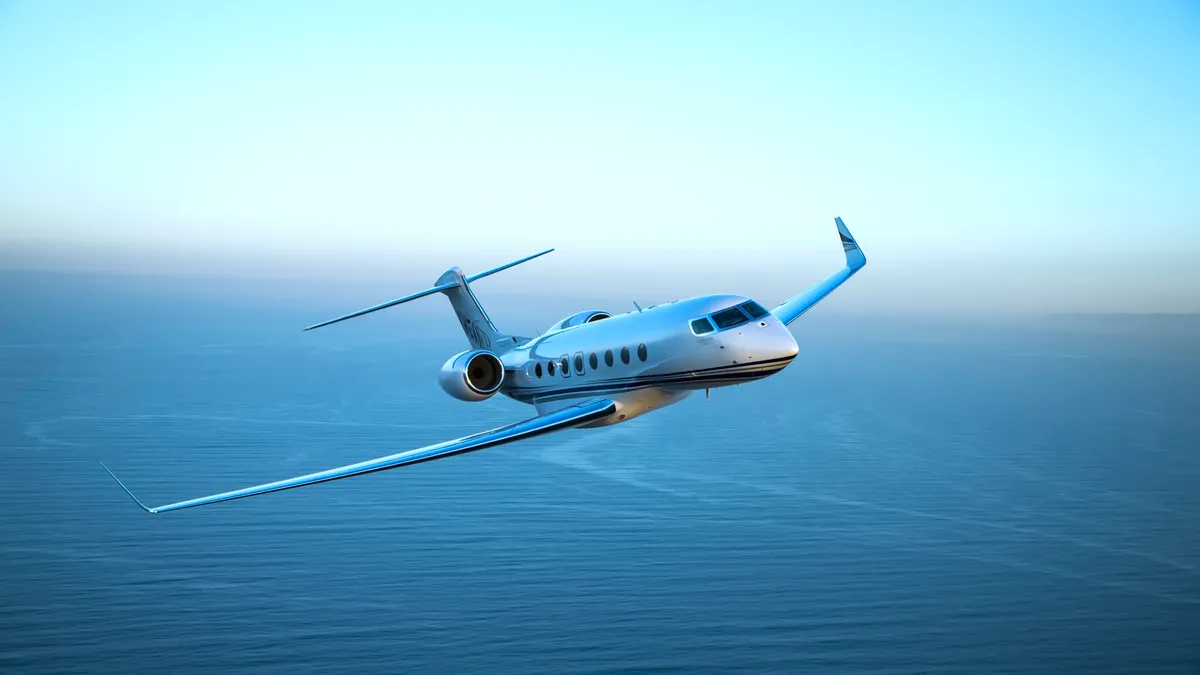 A Gulfstream aircraft flies in the air with a blue sky behind it.