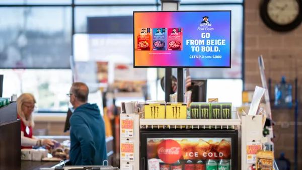 TV screen mounted at a checkout aisle of a grocery store advertising Quaker Oats products