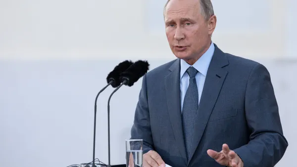 Russian President Vladimir Putin speaking at a podium with a microphone.