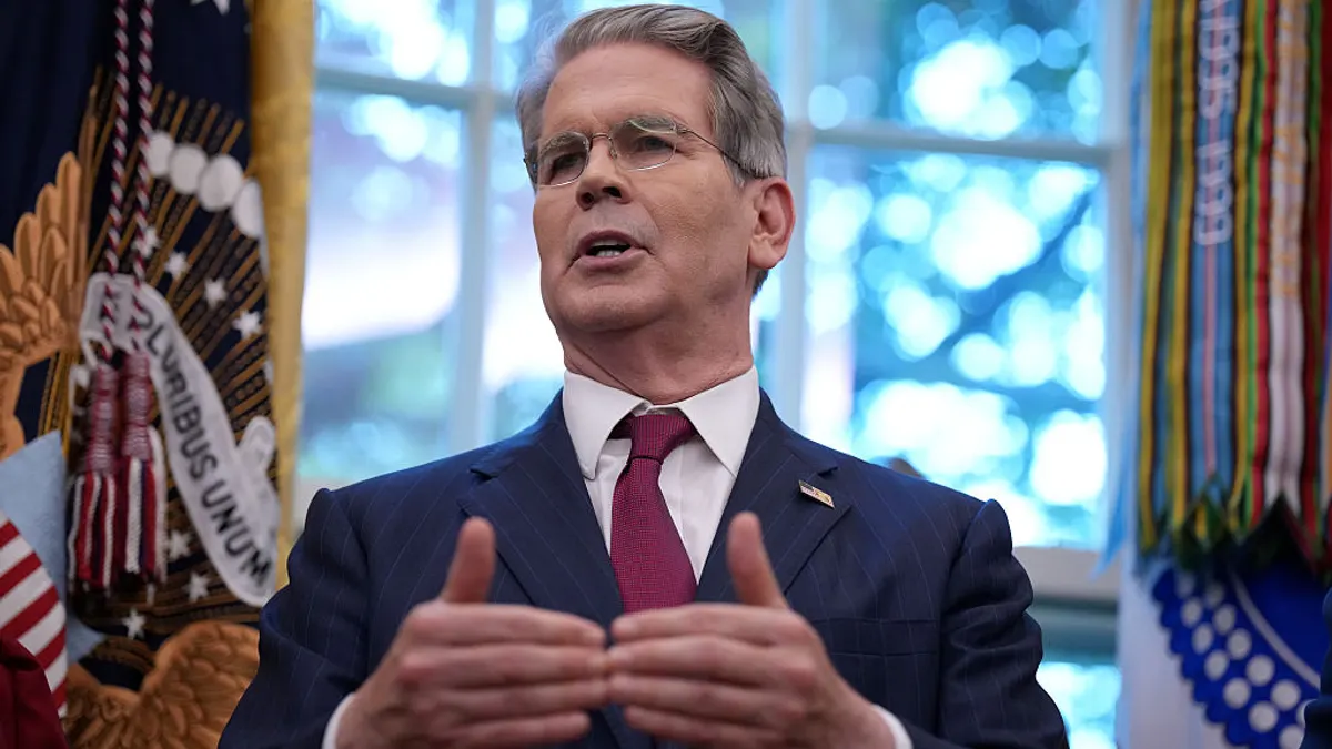 Treasury Secretary Scott Bessent speaks in front of a window while gesturing with his hands