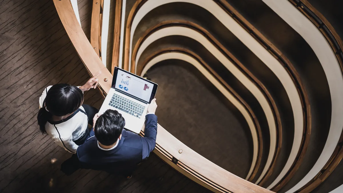 Two people look at a laptop, as seen from overhead.