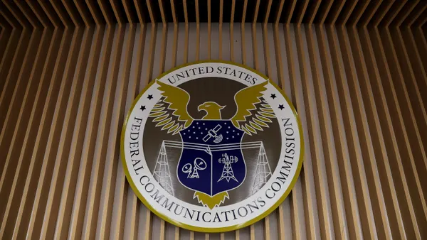 A blue, yellow and white circular sign hangs on a wall that says "United States Federal Communications Commission."