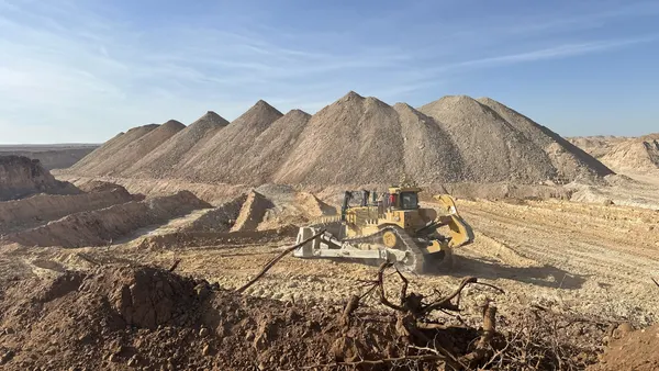 A distant view of a piece of heavy equipment on a dirt-filled scenery.