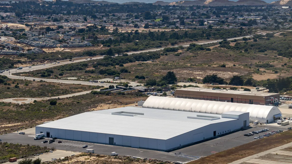 A large white building and a white hangar next to it