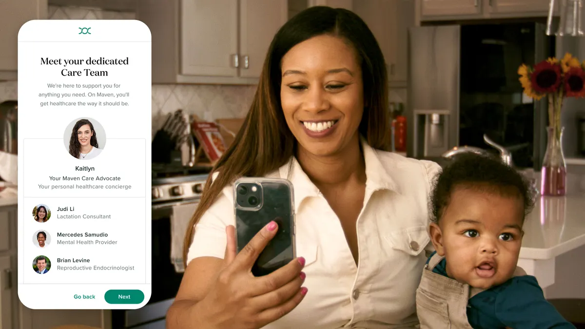 A woman smiles at her phone while holding her son.