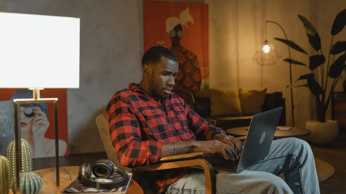 A Black man works on a laptop at night