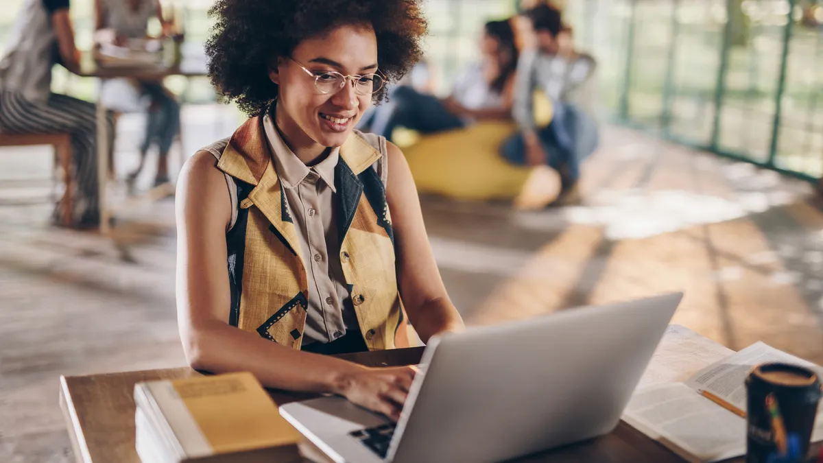 Young happy student using laptop while learning for her exams.