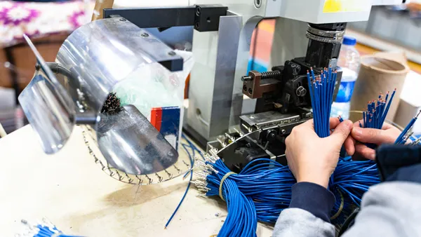 An employee working with machine parts checks industrial equipment cables.