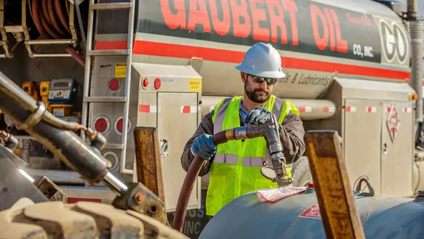 A photo of a person filling up a fuel tank from a tanker truck. Text on the truck reads Gaubert Oil Co, Inc. GO."