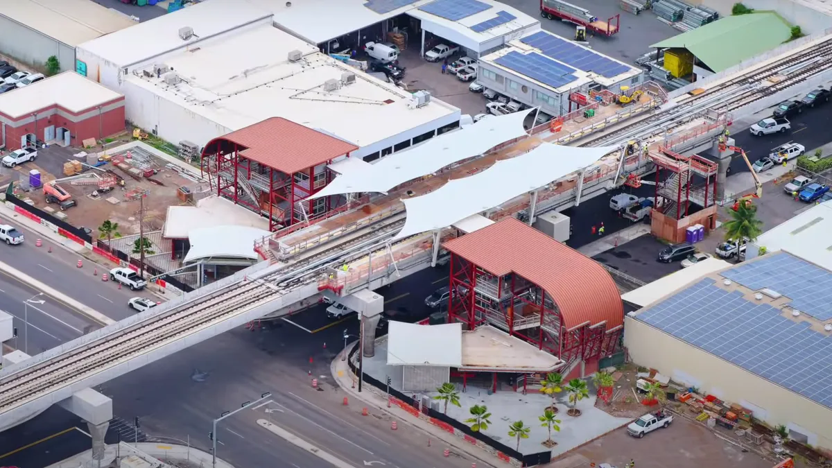 Aerial view of rail tracks running horizontally, bisected by a white-topped station.