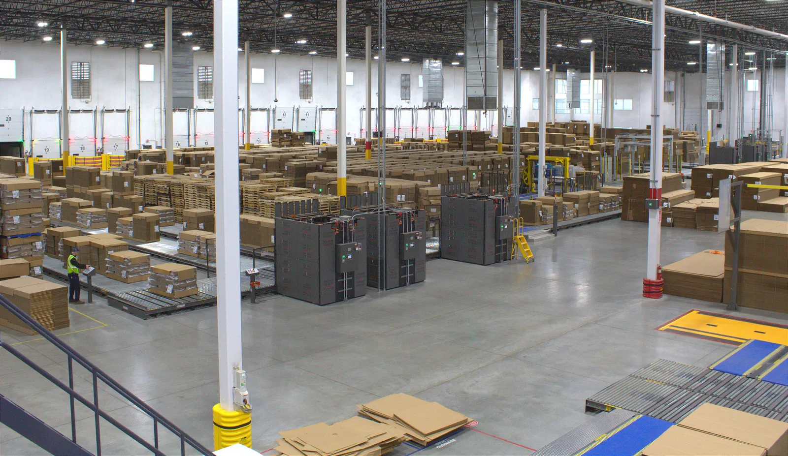 An aerial view of hundreds of stacks of flat corrugated boxes and pallets in an industrial facility.