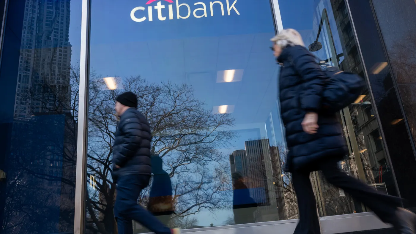 Two people walk by a Citi branch in a downtown setting