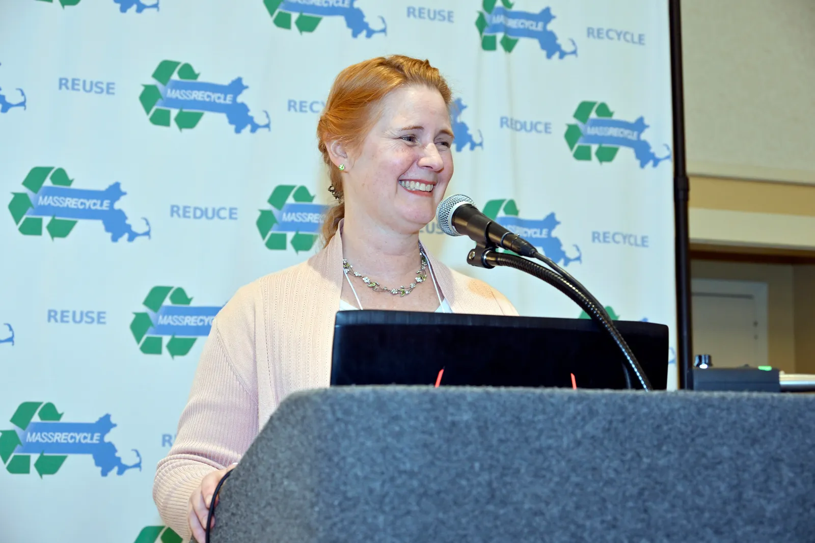 Gretchen Carey, president of MassRecycle, speaks at a podium during a conference