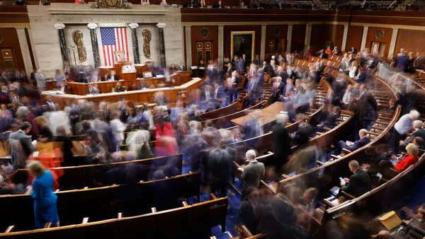 blurred members of congress shuffle around in chamber