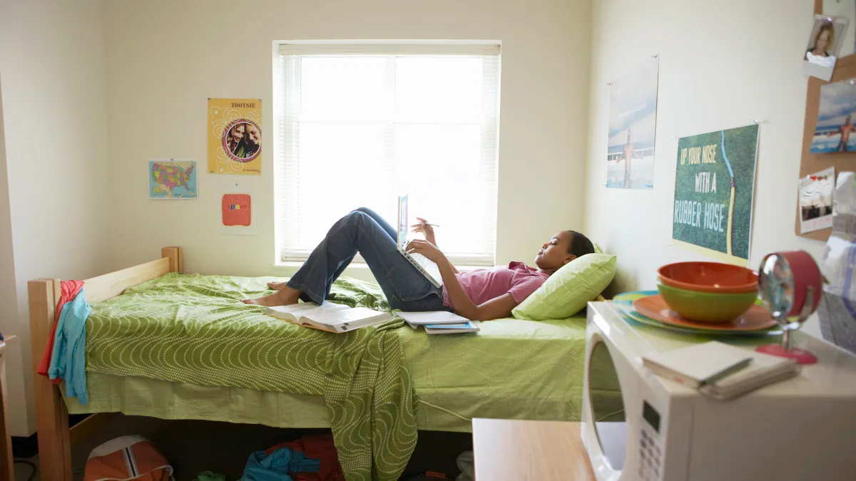 A college student lays in her bed in a college dormitory.