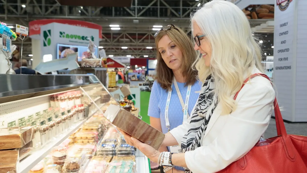 2 woman in a store, looking at a menu/catalog