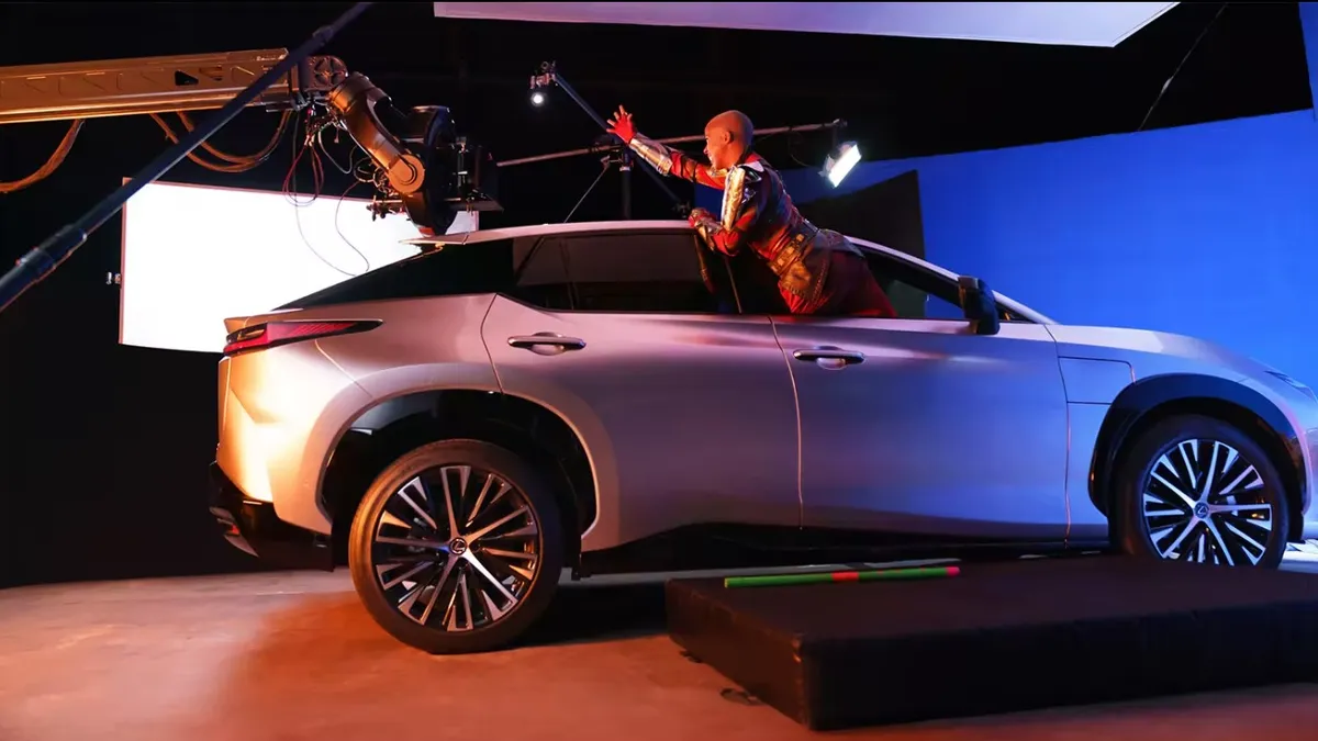 A behind-the-scenes photo shows a 'Black Panther' actor reaching out of the front seat window of a rigged-up Lexus against a blue-screen background.