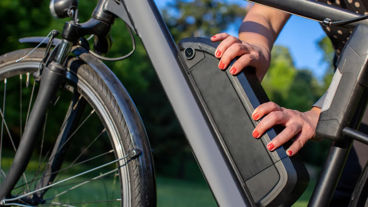 woman holding an electric bike battery mounted on frame