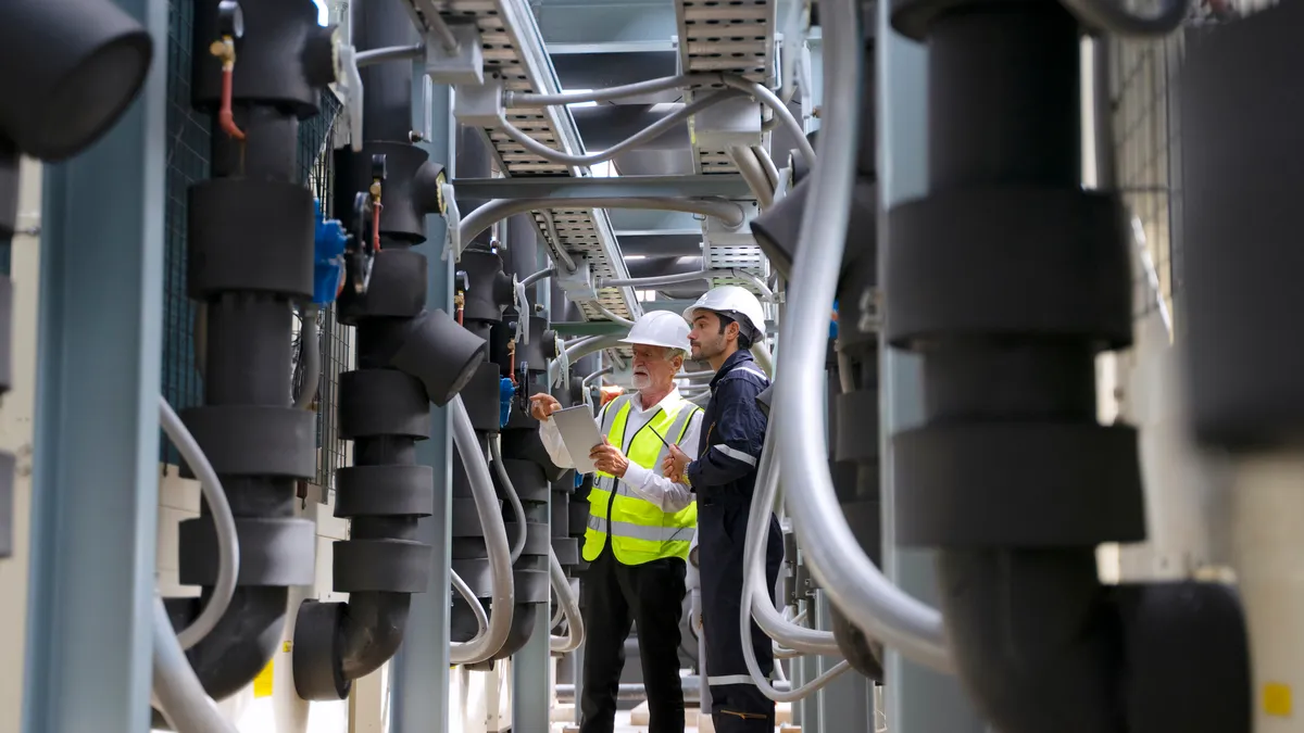 An technician looks at readings on a rooftop HVAC unit.