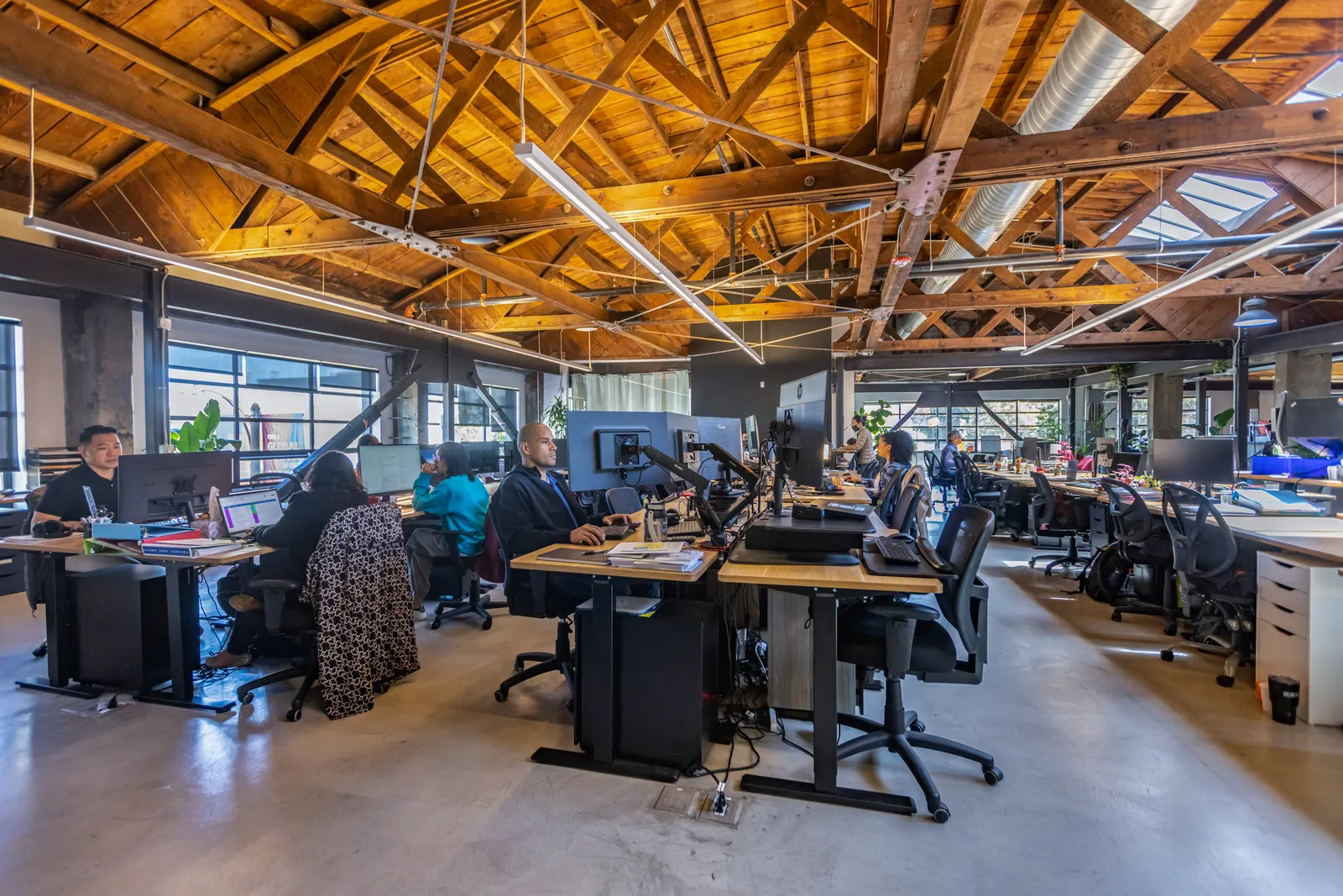A wide-angle view of a corporate office with several people working on computers.