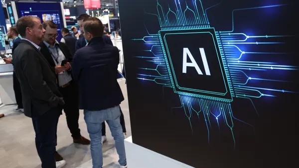 Several men stand next to a display that shows the letters "AI" inside a square whose edges are designed to resemble those of a microchip