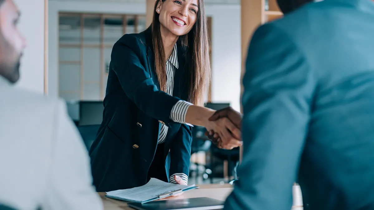 Women shakes hands with man at a business meeting.