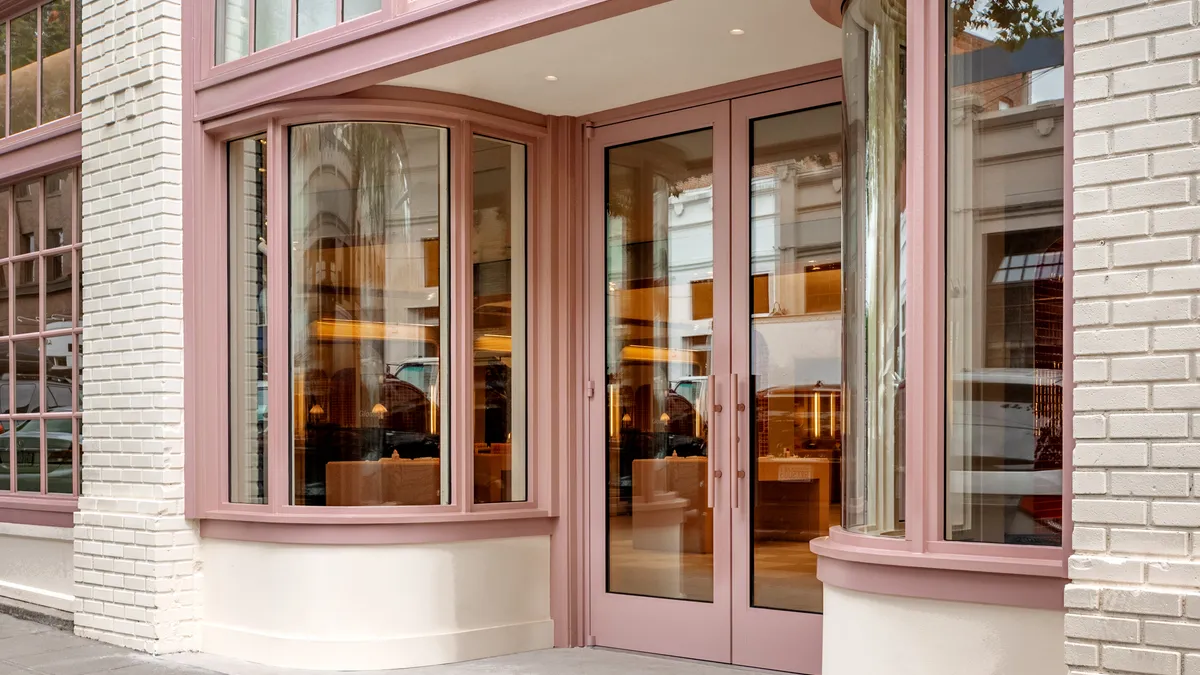 Exterior shot of a Glossier logo on its storefront.