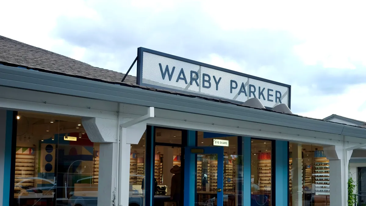 A sign above an eyewear store reads "Warby Parker."