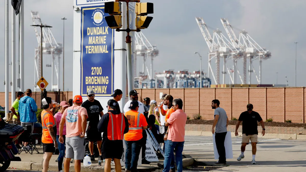 A group of dockworkers gather outside an ocean terminal.