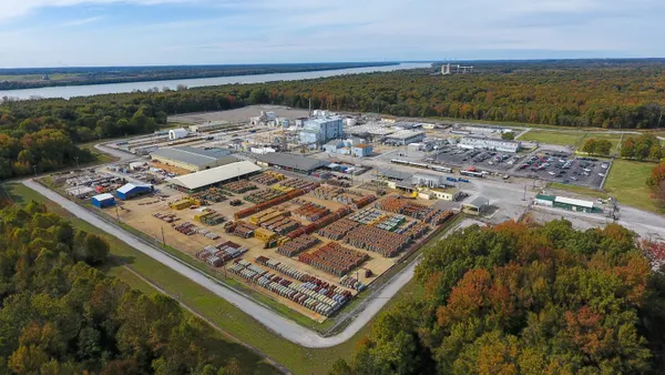 An industrial facility surrounded by a parking lot and trees.