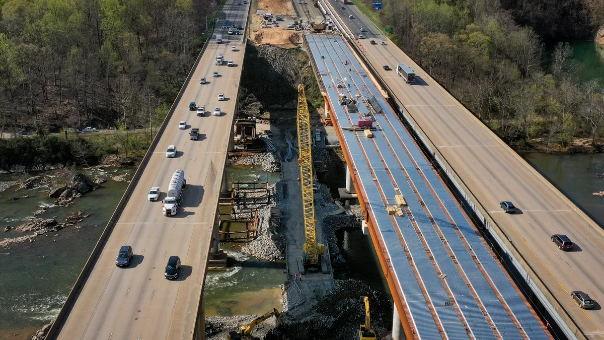 In an aerial view, vehicles on a two-lane highway travel past a construction project.