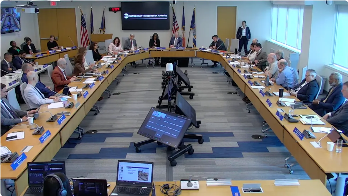 Men and women around a large U-shaped desk.