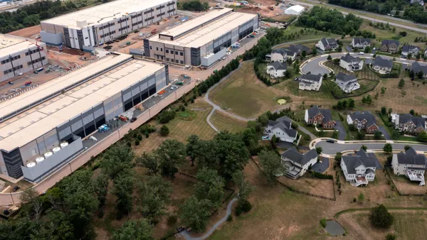 An aerial view of houses next to large industrial buildings.