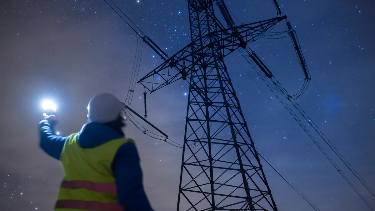 Electricity engineer working on Electrical Pylons Translation, checking the condition of the Electrical Power Pole components at night.