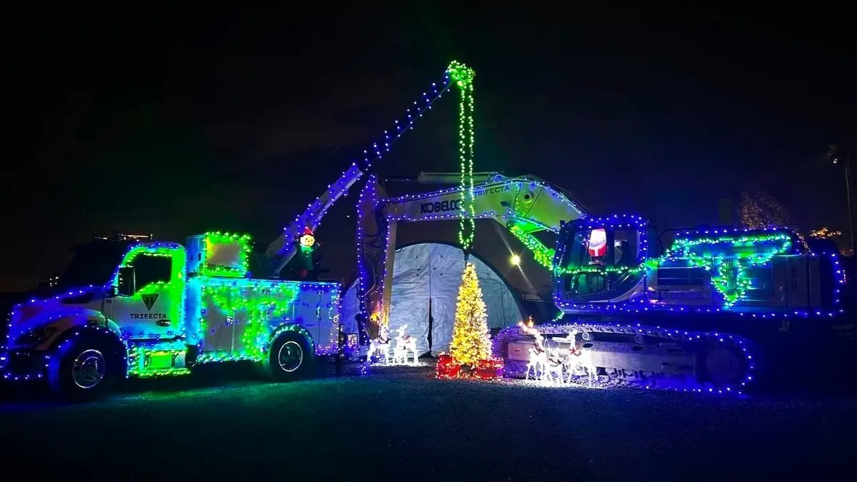 A cement mixer and a mechanics truck are decorated in bright holiday lights amid a night backdrop.