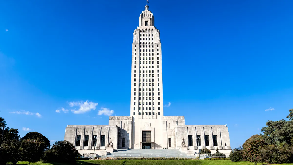 An old-fashioned tall white building with a wide base set against a blue sky.